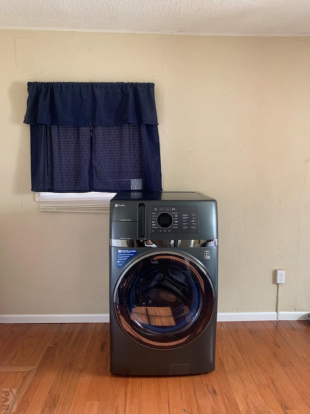 laundry room featuring washer / dryer, a textured ceiling, laundry area, and wood finished floors