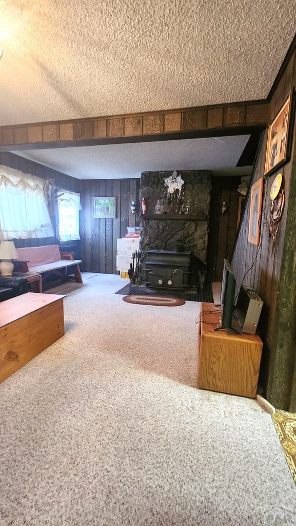 997 Wells Fargo Cir, Jefferson, CO 80456 - carpeted living room featuring a textured ceiling, wood walls, and a fireplace