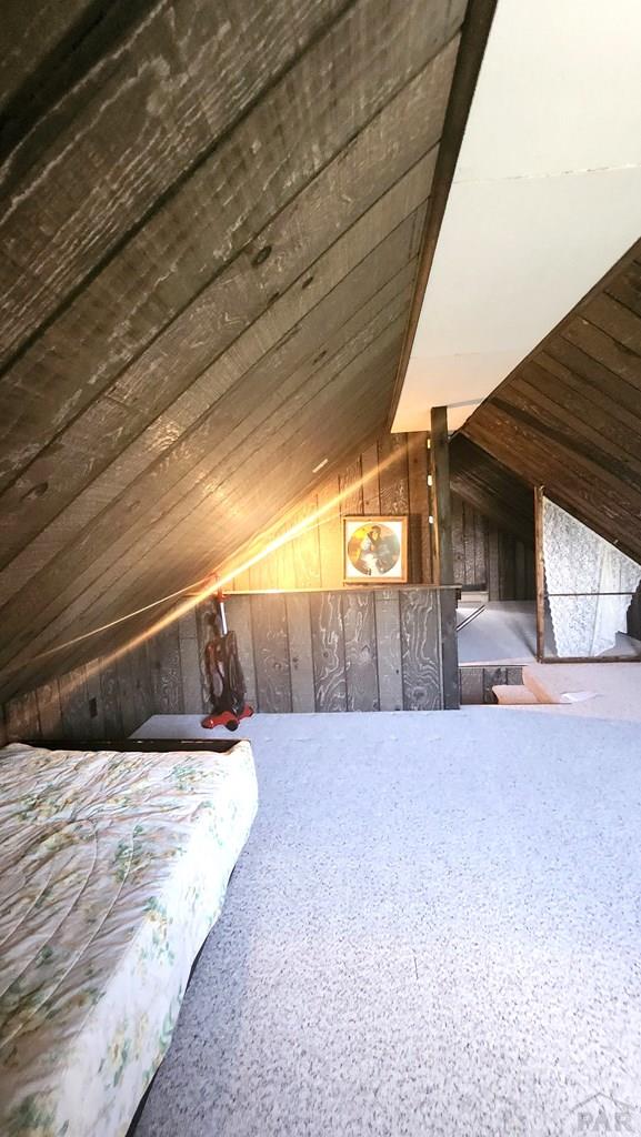 997 Wells Fargo Cir, Jefferson, CO 80456 - bedroom with lofted ceiling and wood walls