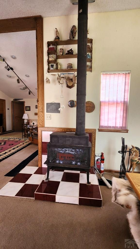 997 Wells Fargo Cir, Jefferson, CO 80456 - living area featuring a wood stove, a textured ceiling, tile patterned floors, and track lighting