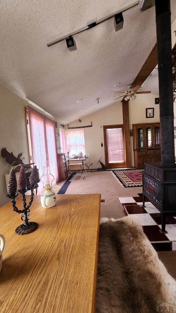 997 Wells Fargo Cir, Jefferson, CO 80456 - carpeted living area featuring a wood stove, a textured ceiling, lofted ceiling, and a ceiling fan