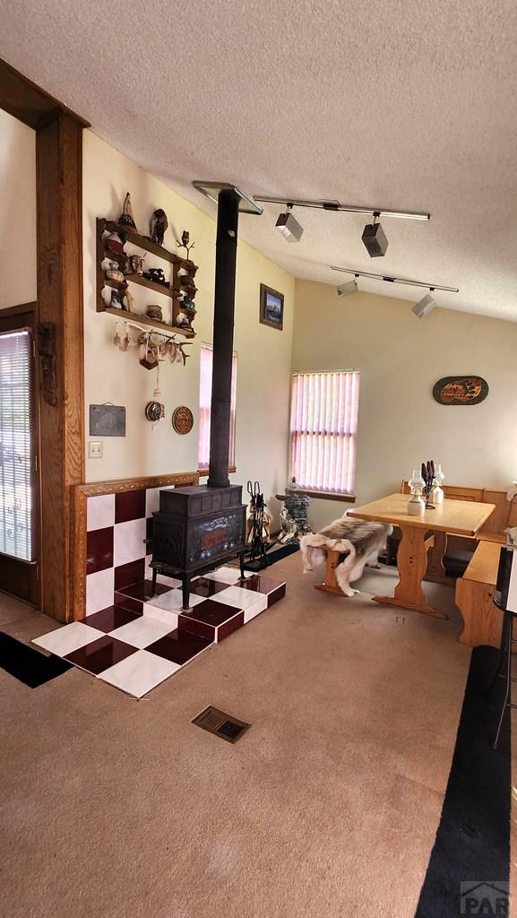 997 Wells Fargo Cir, Jefferson, CO 80456 - carpeted dining space featuring a wood stove and a textured ceiling