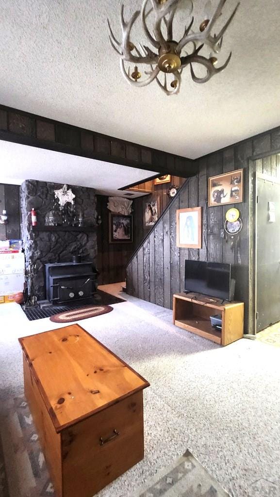997 Wells Fargo Cir, Jefferson, CO 80456 - carpeted living room with a textured ceiling, a wood stove, stairway, and wooden walls