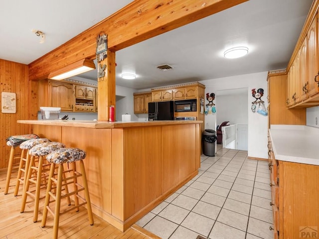 1505 Center Ln, Pueblo, CO 81006 - kitchen featuring a peninsula, black appliances, a breakfast bar area, light countertops, and light tile patterned flooring