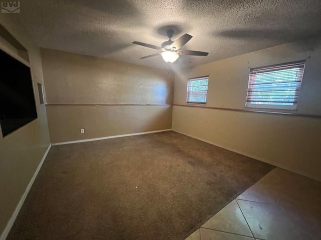 carpeted spare room with ceiling fan, baseboards, a textured ceiling, and tile patterned floors