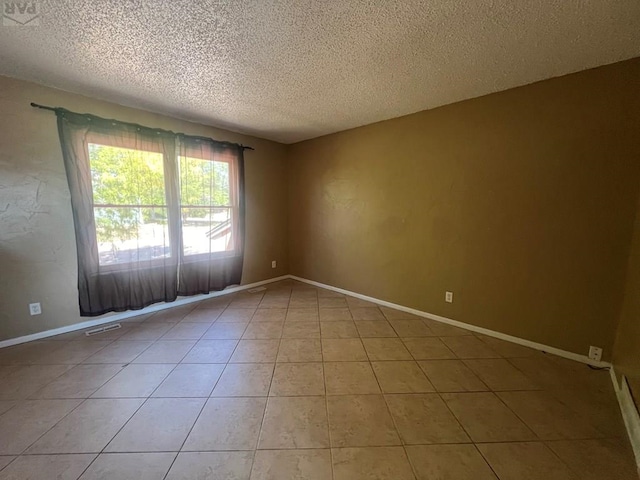 unfurnished room with light tile patterned floors, visible vents, baseboards, and a textured ceiling