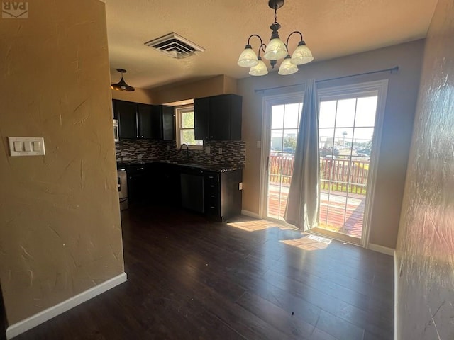 kitchen featuring dark cabinets, dark wood-style flooring, visible vents, hanging light fixtures, and backsplash