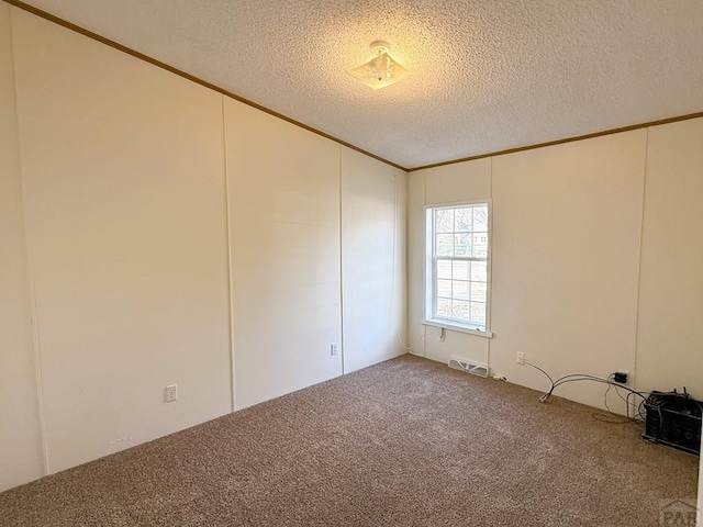 carpeted spare room with visible vents, crown molding, and a textured ceiling