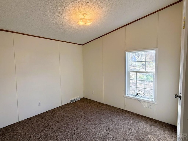 carpeted spare room with vaulted ceiling, visible vents, and a textured ceiling