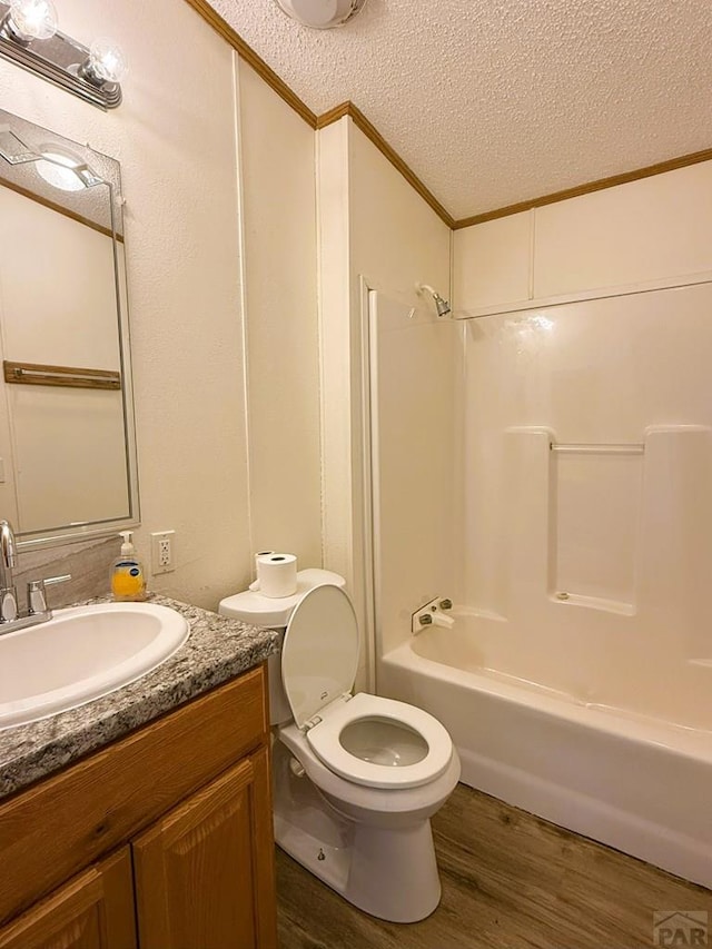 bathroom with a textured ceiling, wood finished floors, toilet, vanity, and shower / tub combination