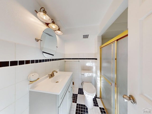 bathroom with toilet, vanity, visible vents, a shower stall, and tile patterned floors