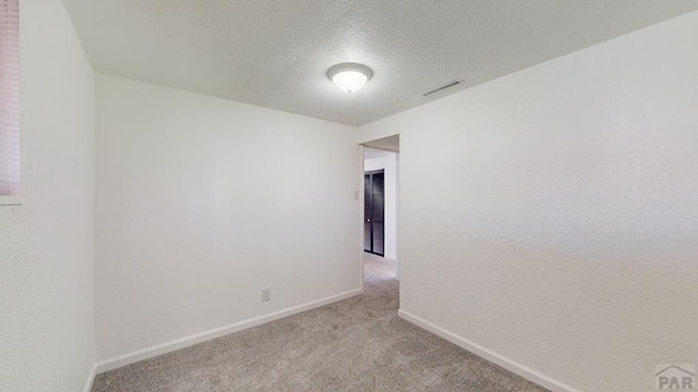 unfurnished room featuring light colored carpet, visible vents, a textured ceiling, and baseboards