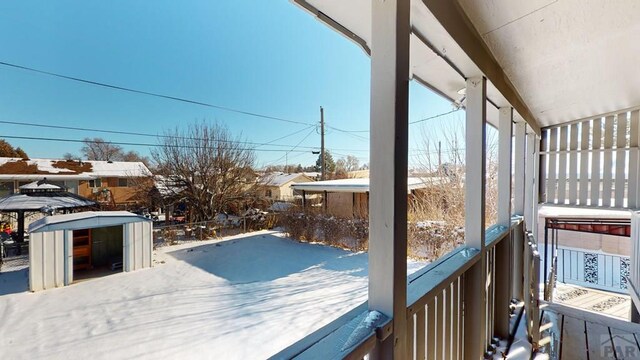 snow covered deck with an outbuilding and a storage unit