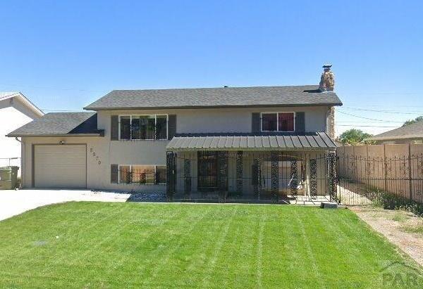 view of front facade featuring fence, a front lawn, and stucco siding