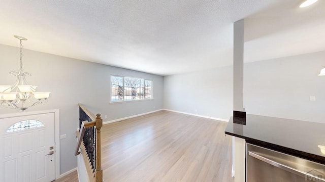 foyer entrance featuring light wood-style flooring, baseboards, and an inviting chandelier