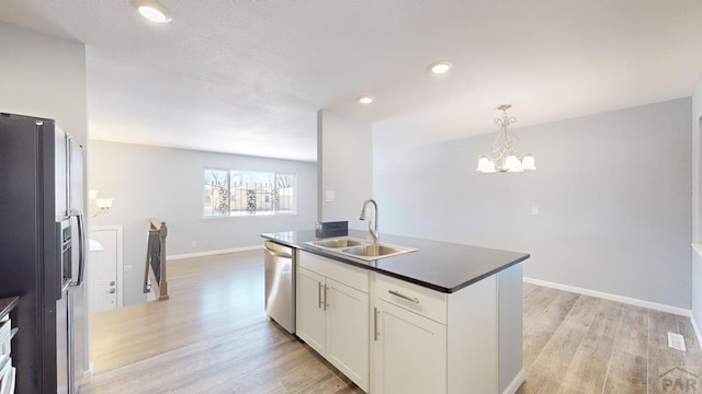 kitchen with dishwasher, dark countertops, black fridge, white cabinetry, and a sink