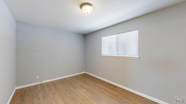 empty room with light wood-style floors and baseboards