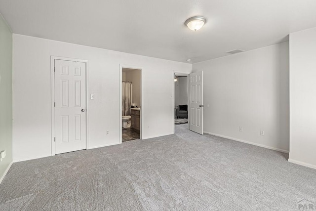 unfurnished bedroom with baseboards, carpet, ensuite bath, and visible vents