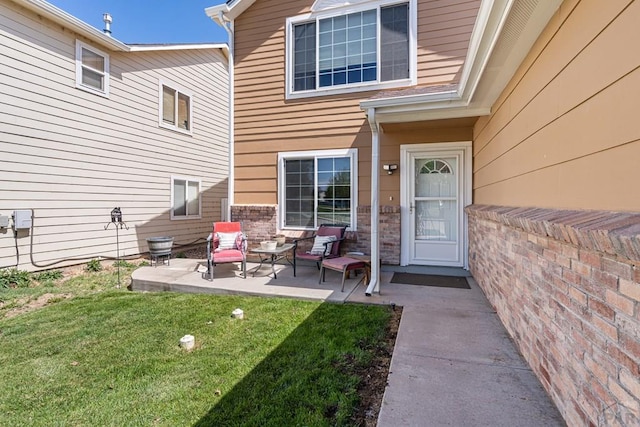 view of exterior entry with a yard and a patio