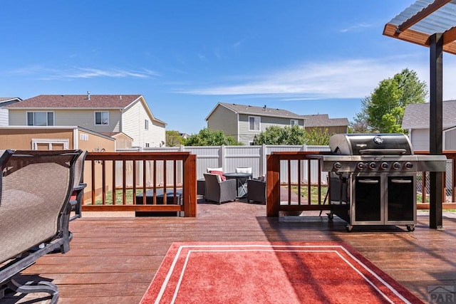 wooden terrace with a residential view, fence, and area for grilling
