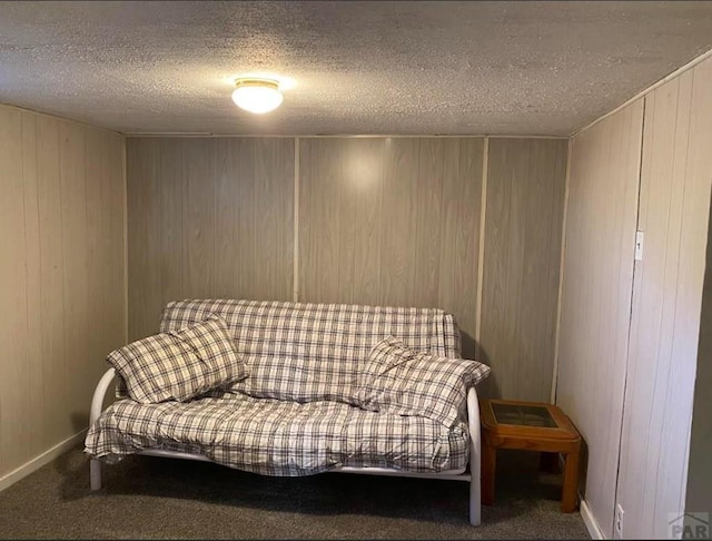 sitting room with carpet floors, wood walls, baseboards, and a textured ceiling