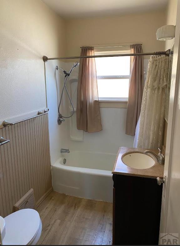 bathroom featuring toilet, shower / bath combo, wood finished floors, and vanity