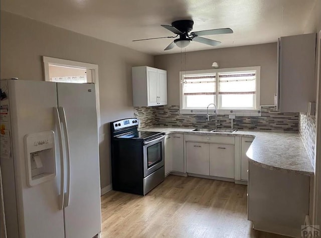 kitchen featuring light countertops, electric range, white cabinets, a sink, and white fridge with ice dispenser