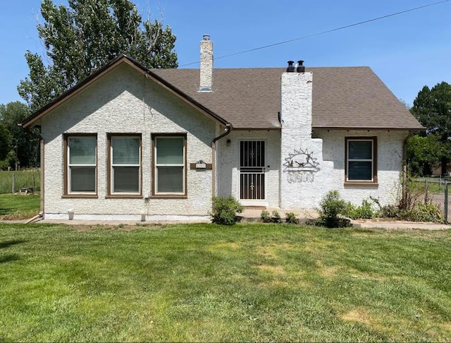 view of front of home with a shingled roof, a chimney, and a front yard