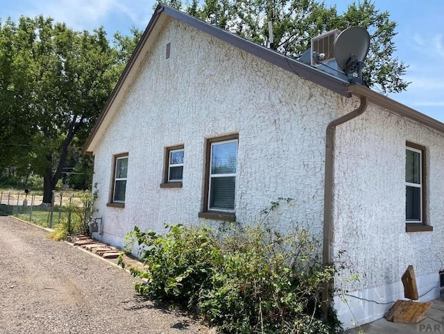 view of side of property with fence and stucco siding