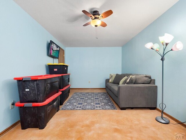 carpeted living room featuring ceiling fan and baseboards