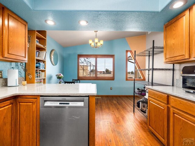 kitchen featuring brown cabinetry, hanging light fixtures, a peninsula, and stainless steel dishwasher