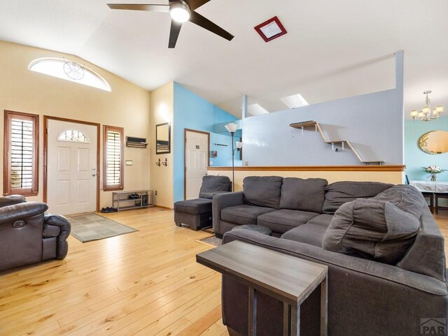 living room with light wood-style floors, high vaulted ceiling, and ceiling fan with notable chandelier