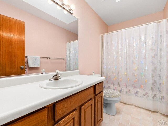 bathroom with toilet, a shower with shower curtain, a skylight, and vanity