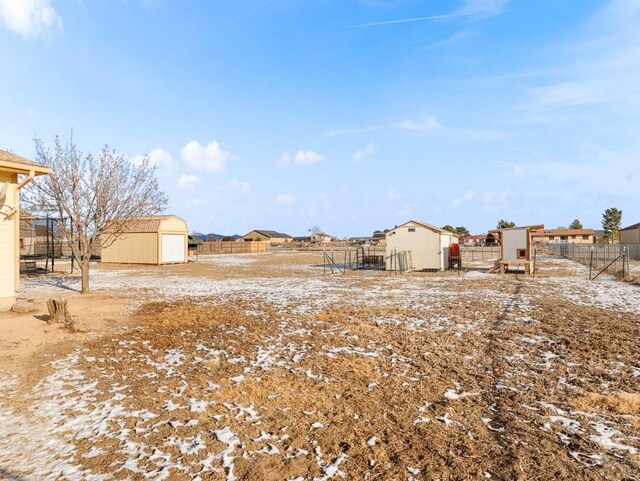 view of yard featuring fence, a storage unit, and an outdoor structure