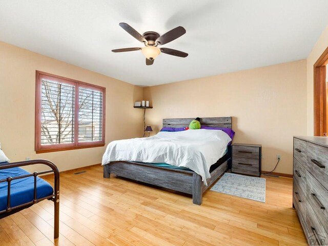 bedroom with light wood-type flooring, baseboards, and a ceiling fan