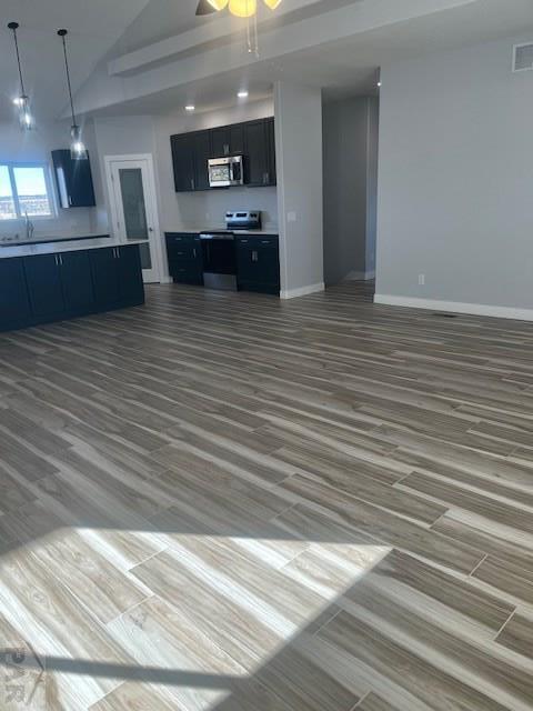 kitchen featuring light countertops, appliances with stainless steel finishes, open floor plan, ceiling fan, and dark cabinetry