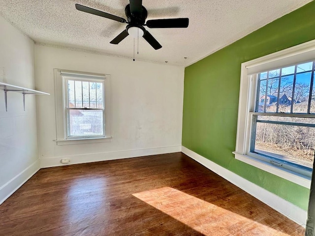 unfurnished room with dark wood-style floors, a textured ceiling, baseboards, and a ceiling fan