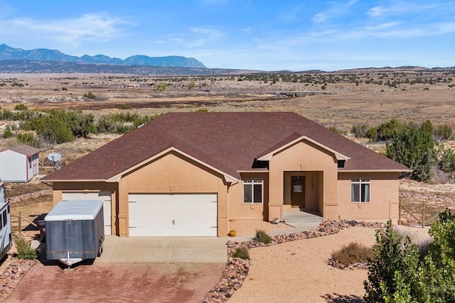 ranch-style home with driveway, a garage, a mountain view, and stucco siding