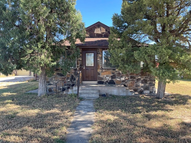 doorway to property featuring stone siding and a yard