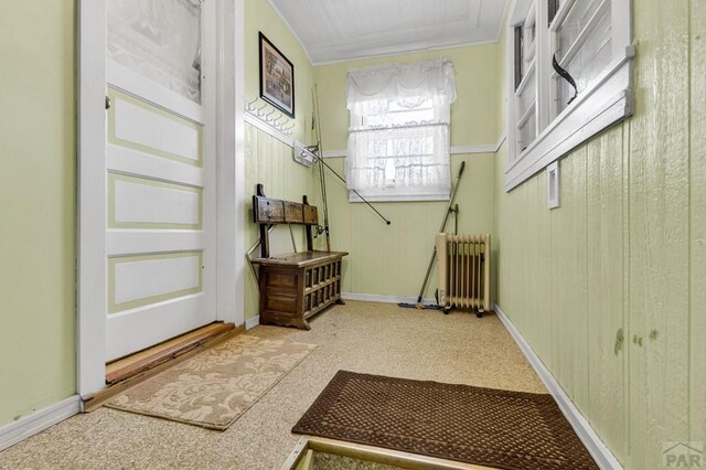 entryway with wood walls, radiator heating unit, and baseboards