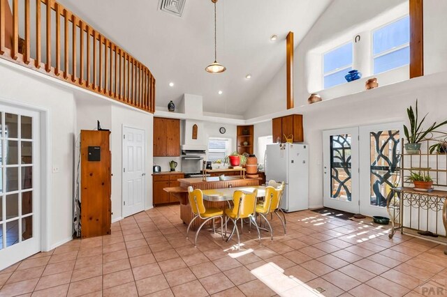 kitchen featuring visible vents, a breakfast bar area, brown cabinetry, and freestanding refrigerator