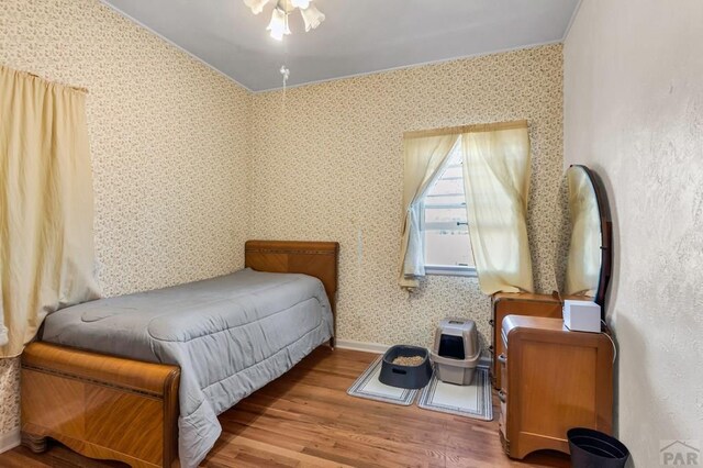 bedroom featuring wallpapered walls and wood finished floors