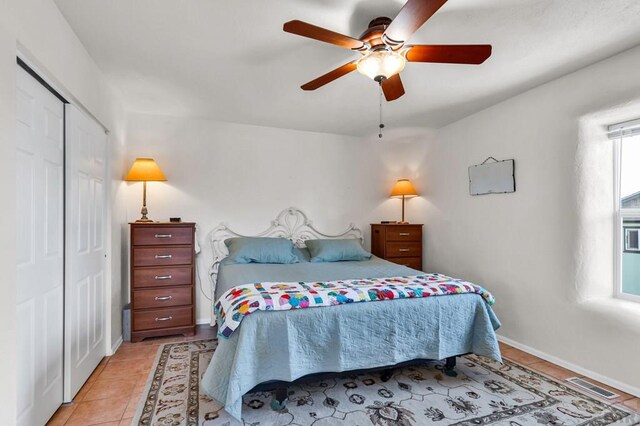 bedroom with light tile patterned floors, a ceiling fan, visible vents, baseboards, and a closet