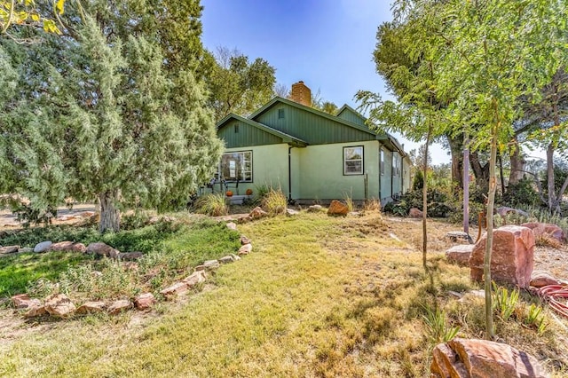 rear view of property featuring a chimney and a lawn