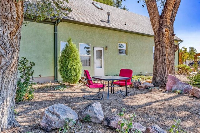 back of property featuring a shingled roof and stucco siding