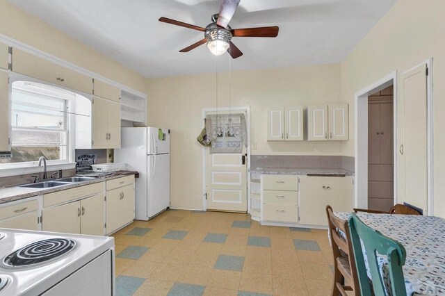 kitchen with white appliances, white cabinetry, a sink, and light floors