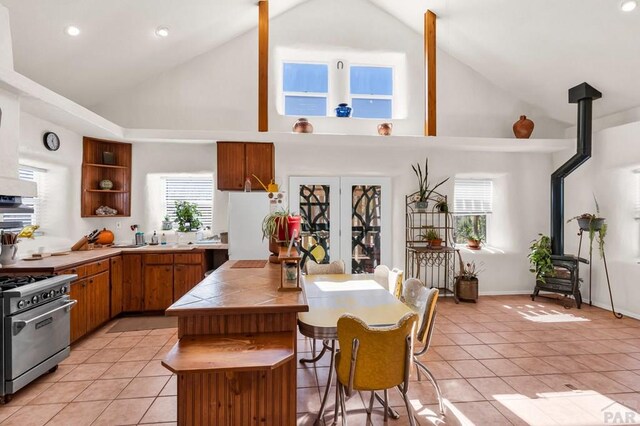 kitchen with a wood stove, light tile patterned floors, high end stove, and freestanding refrigerator