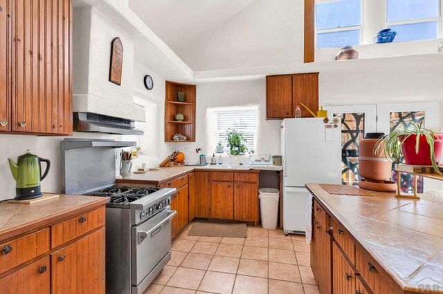 kitchen with light tile patterned floors, freestanding refrigerator, high end stove, and tile counters