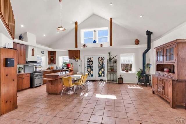 kitchen featuring a breakfast bar area, open shelves, high end stainless steel range oven, a wood stove, and light tile patterned flooring