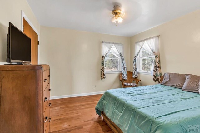 bedroom featuring light wood-type flooring, baseboards, and a ceiling fan